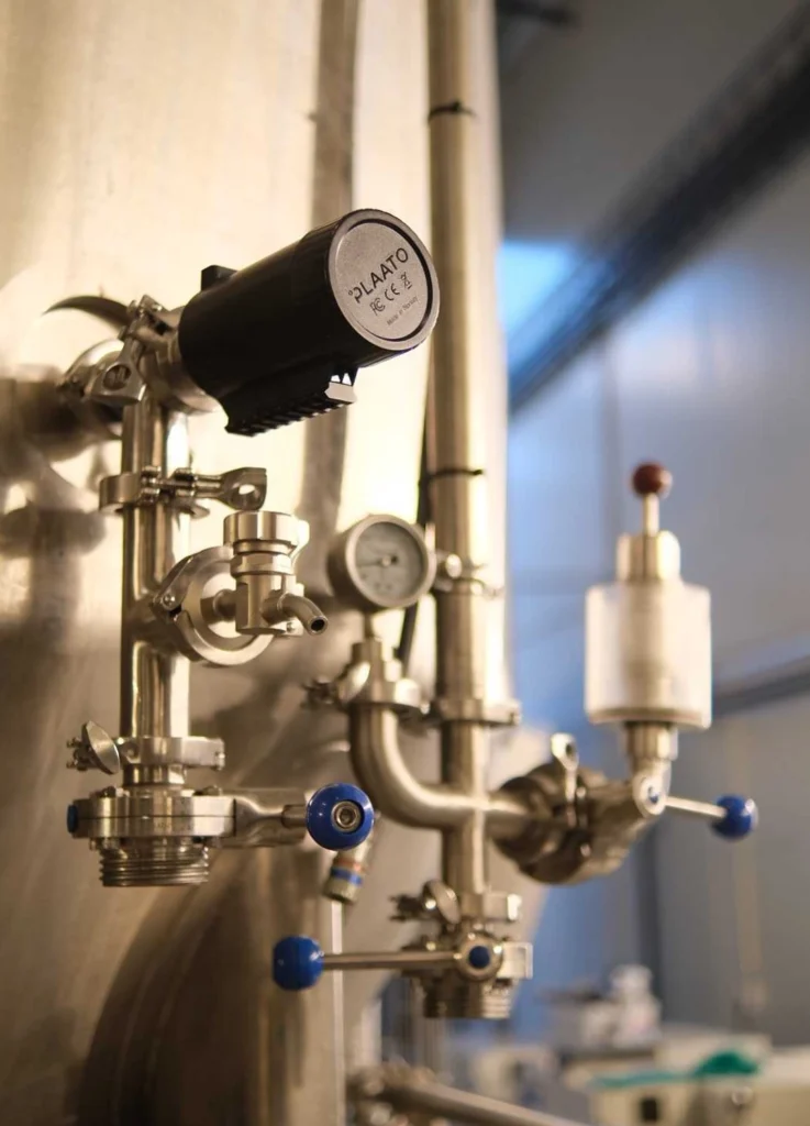 Detailaufnahme eines PLAATO-Sensors und Edelstahl-Ventilsystems in einer Brauanlage
